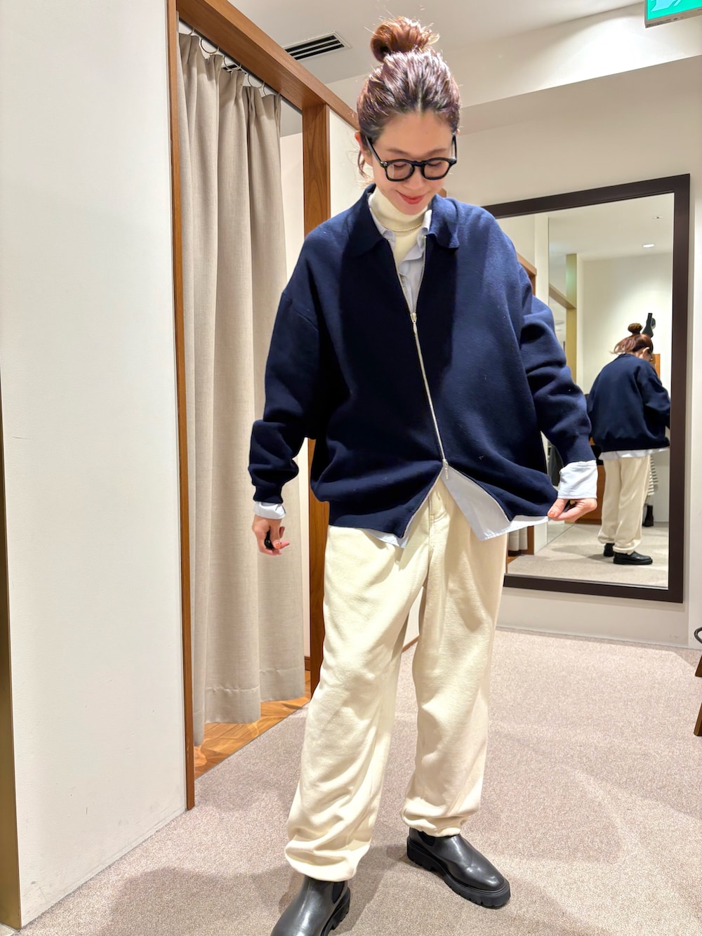 ブラック系のチェスターコート、ホワイト系のその他パンツ、ブラック系のブーツを着用したレディースの冬コーディネートの5枚目の写真