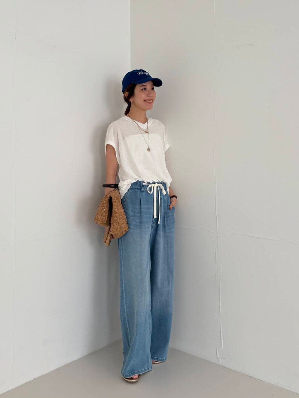 ホワイト系のキャミソール、ブルー系のデニムパンツ、ホワイト系のニット/セーターを着用したレディースの夏コーディネートの5枚目の写真
