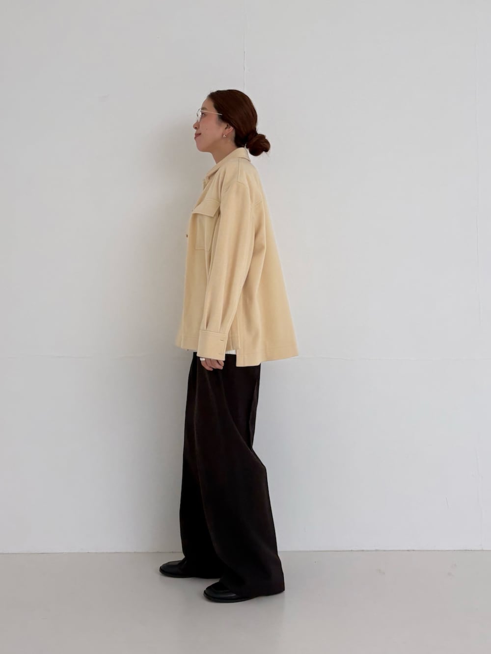 ホワイト系のニット/セーター、ブラウン系のその他パンツ、ゴールド系のメガネを着用したレディースの秋コーディネートの2枚目の写真