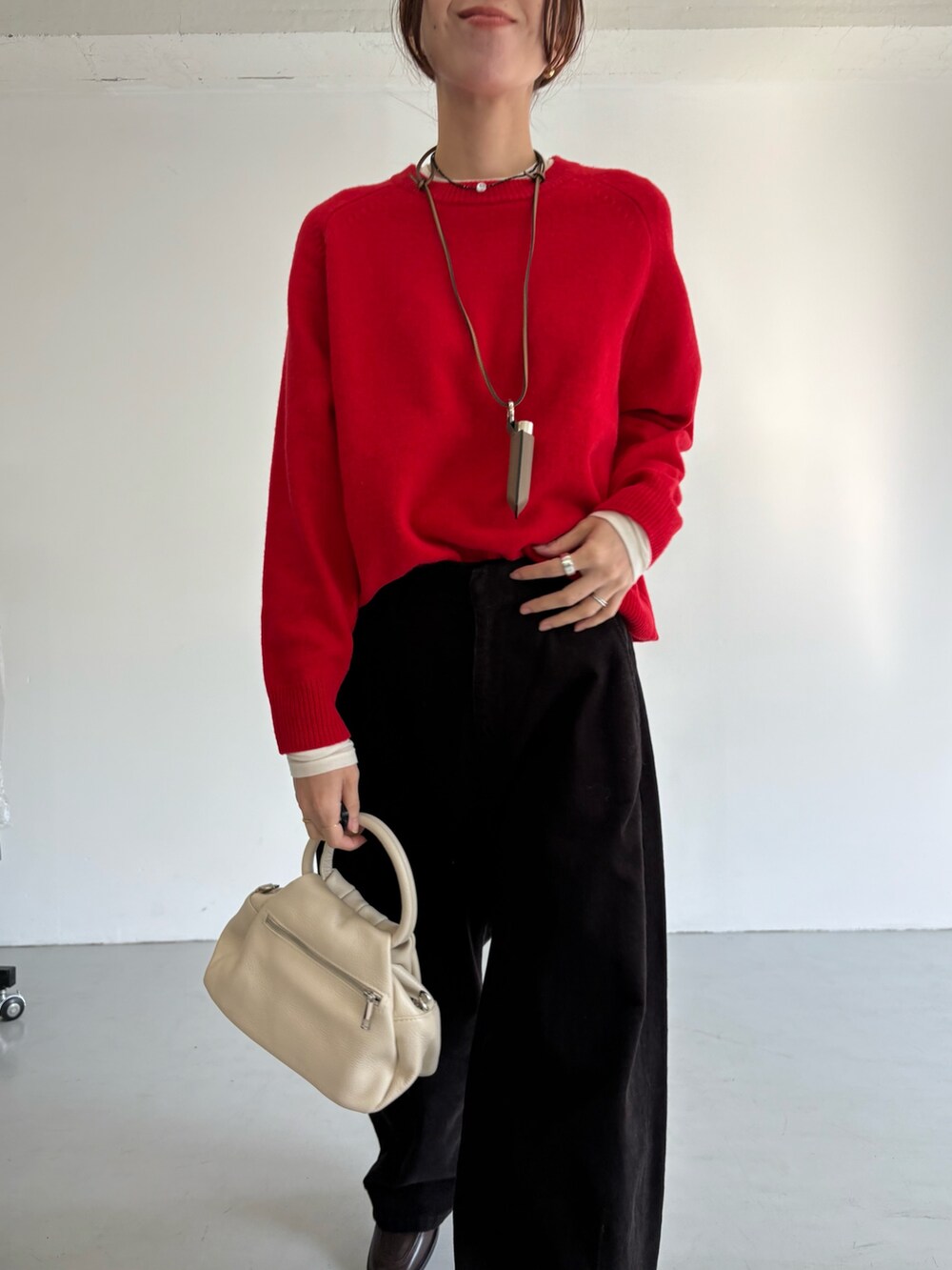 グレー系のその他パンツ、レッド系のニット/セーター、ブラック系のハンドバッグを着用したレディースの冬コーディネートの7枚目の写真