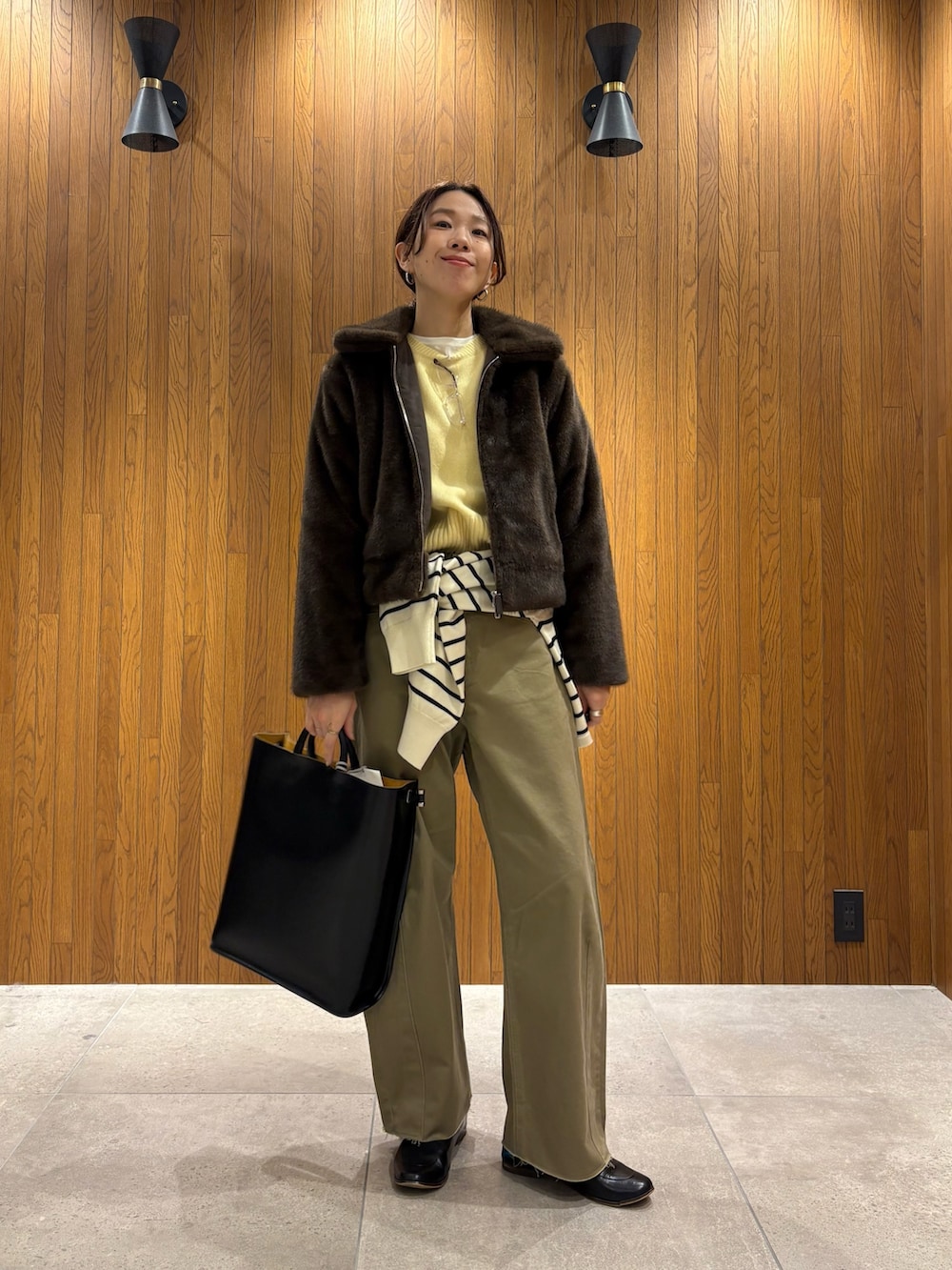 イエロー系のニット/セーター、ベージュ系のその他パンツ、ブラック系のハンドバッグを着用したレディースの冬コーディネートの6枚目の写真