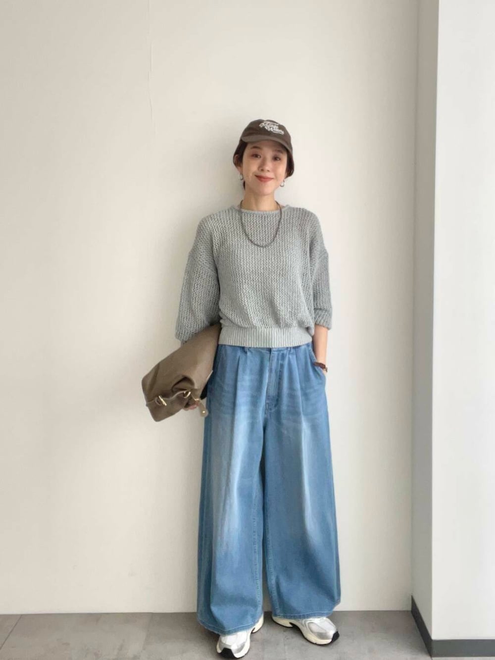 ベージュ系のボストンバッグ、グレー系のニット/セーター、ホワイト系のスニーカーを着用したレディースの春コーディネートの2枚目の写真