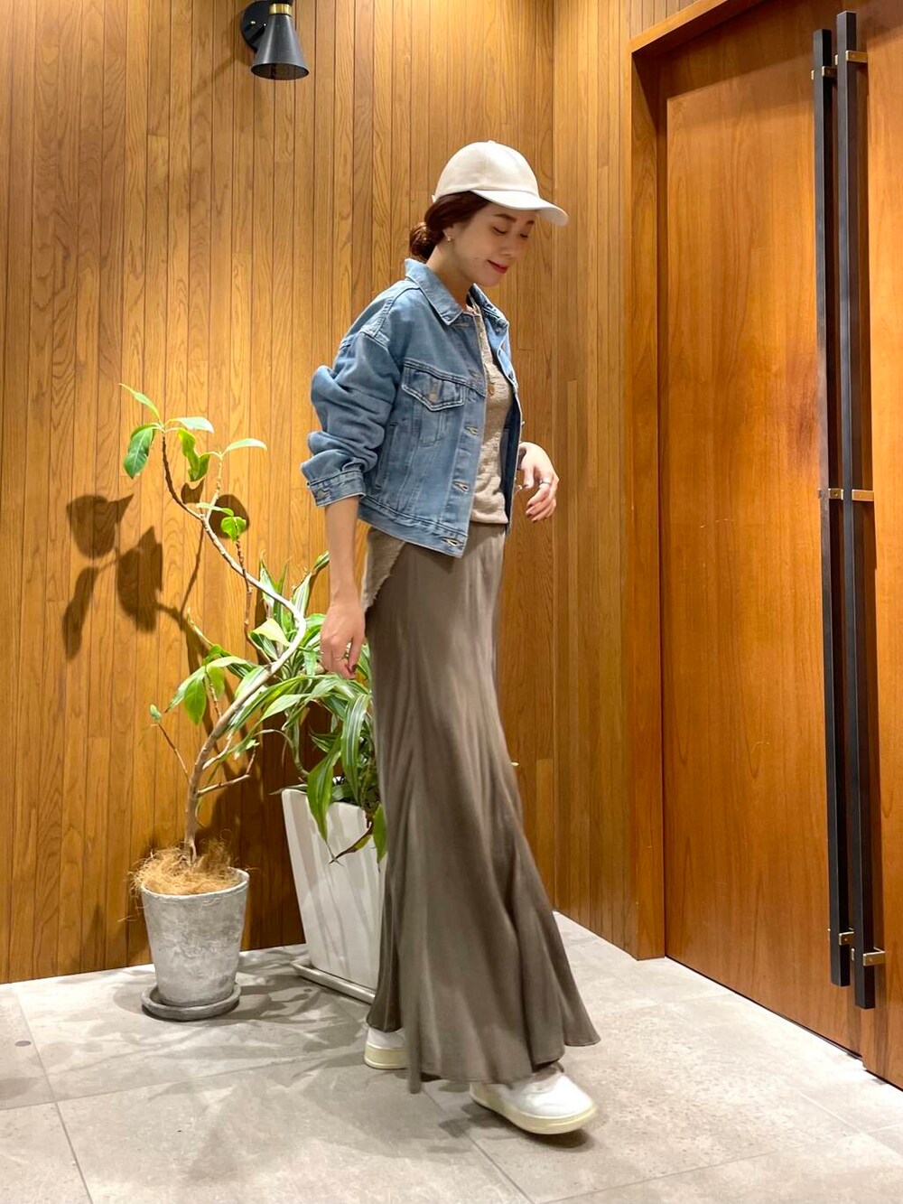 グリーン系のスカート、ブルー系のデニムジャケット、ホワイト系のスニーカーを着用したレディースの秋コーディネートの2枚目の写真