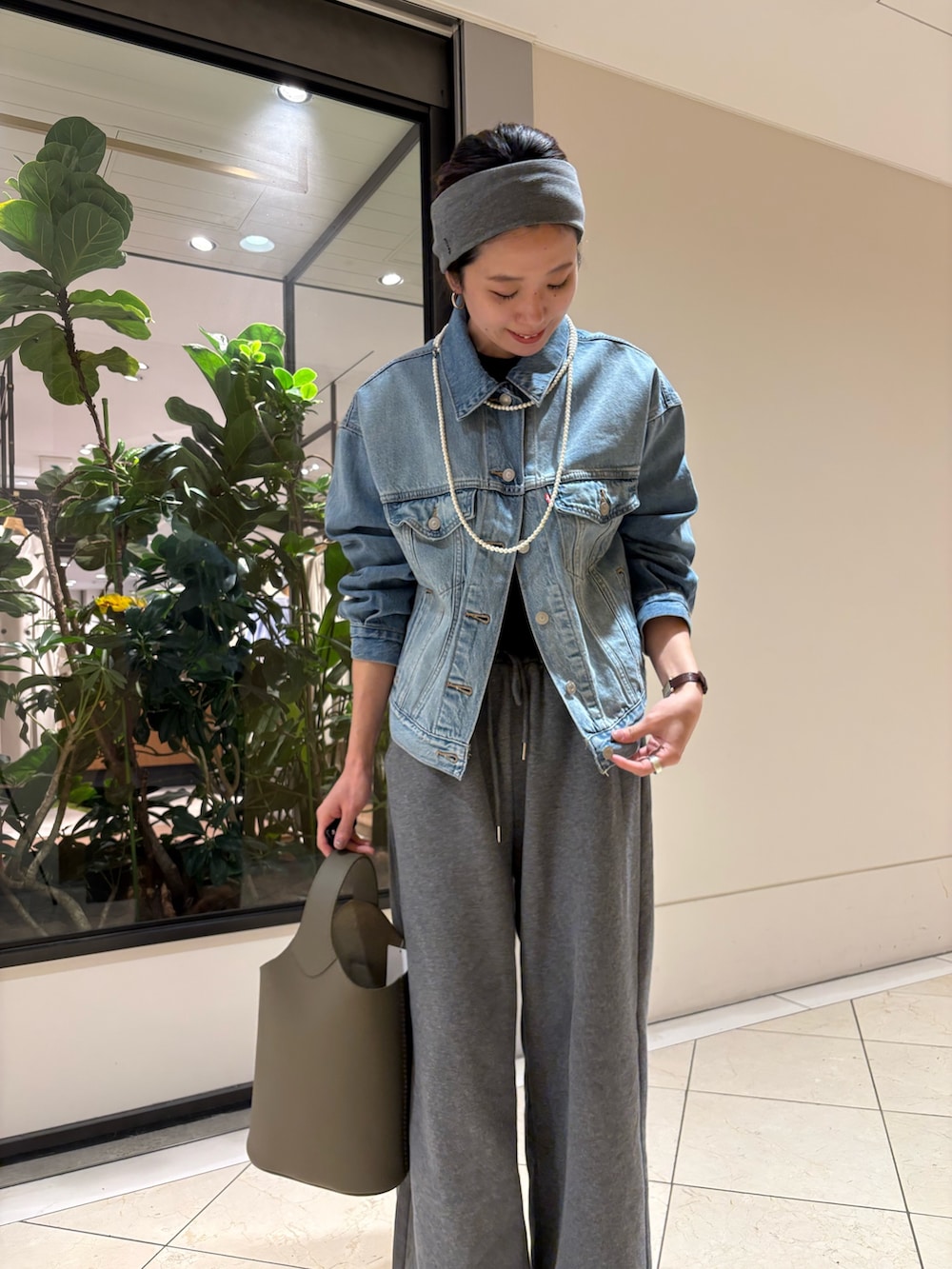 ブルー系のデニムジャケット、グリーン系のハンドバッグ、グレー系のヘアバンドを着用したレディースの春コーディネートの6枚目の写真