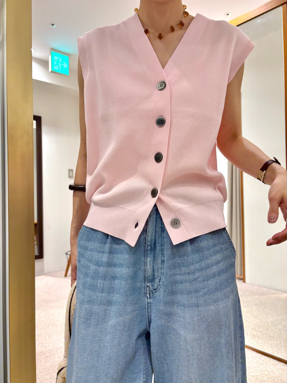 ブルー系のデニムパンツ、ピンク系のベスト、ホワイト系のハンドバッグを着用したレディースの夏コーディネートの6枚目の写真