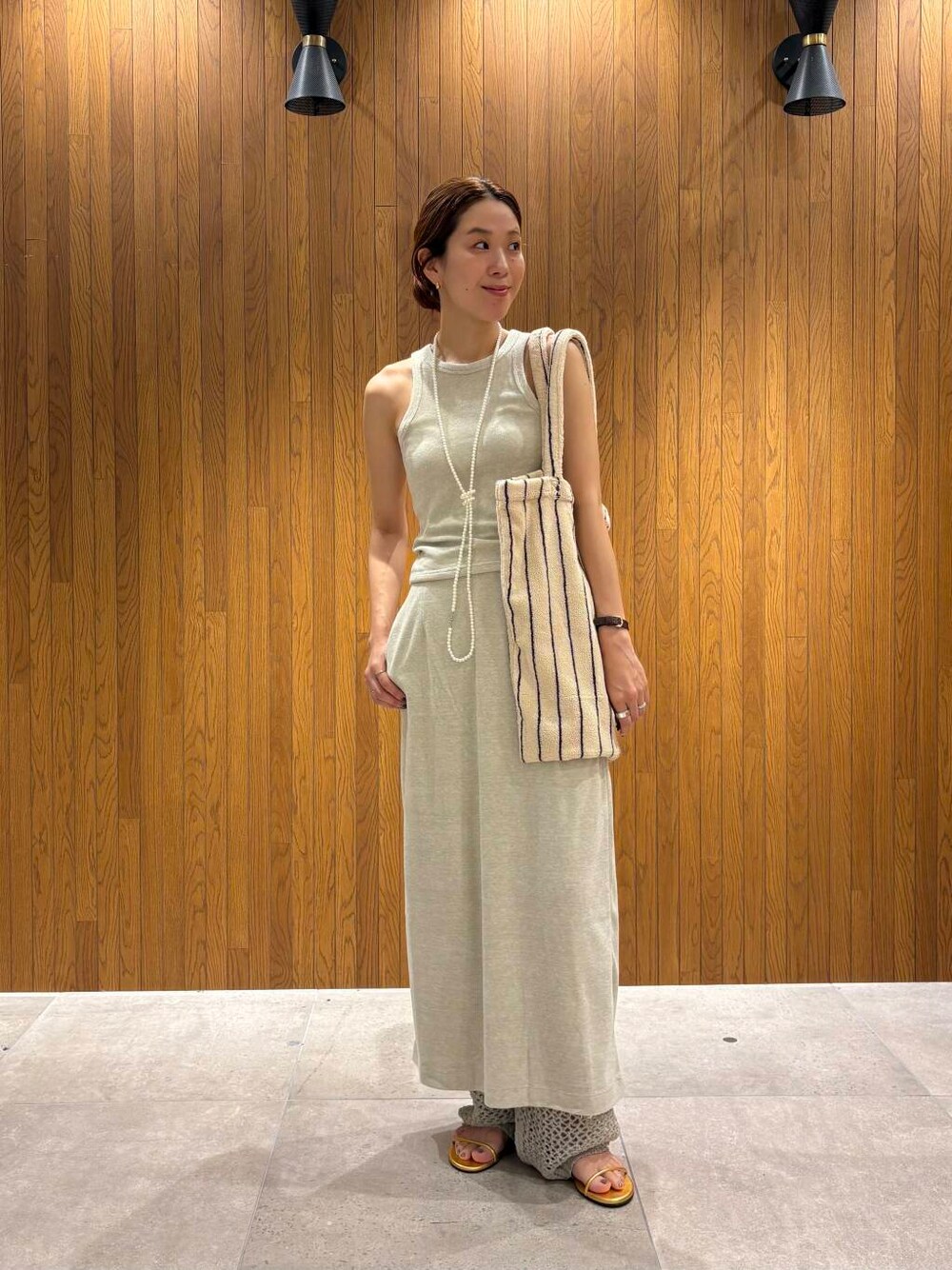 ゴールド系のサンダルを着用したレディースの夏コーディネートの2枚目の写真