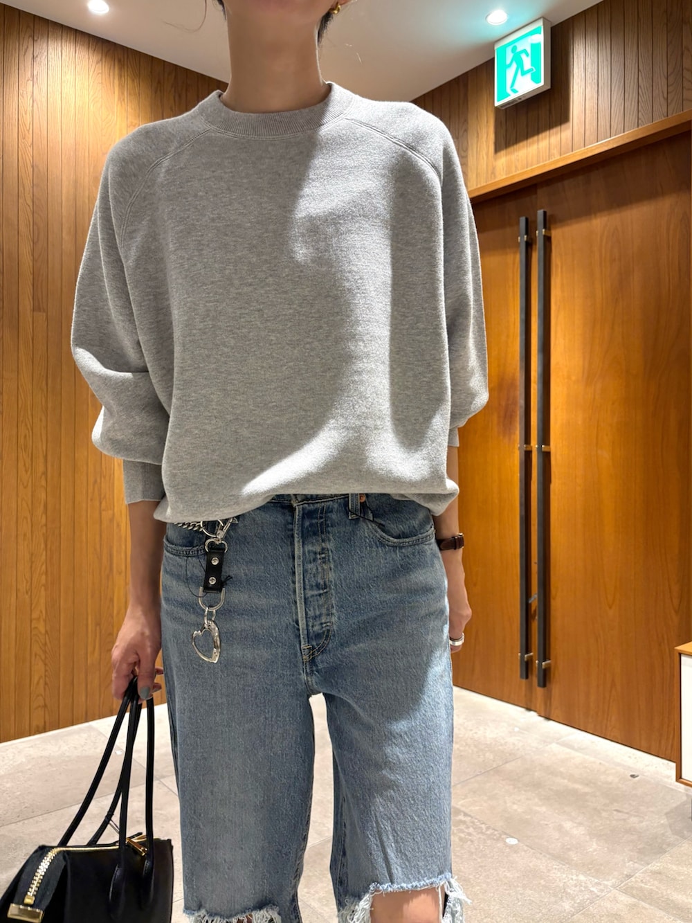 ブルー系のデニムパンツ、グレー系のニット/セーター、ブラック系のショルダーバッグを着用したレディースの秋コーディネートの6枚目の写真