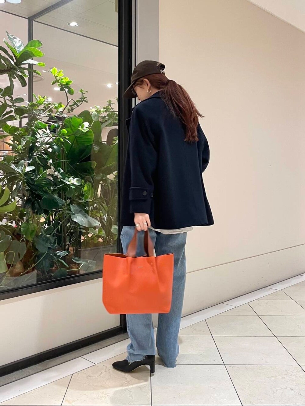 ブルー系のピーコート、ブルー系のデニムパンツ、ブラック系のブーツを着用したレディースの冬コーディネートの5枚目の写真