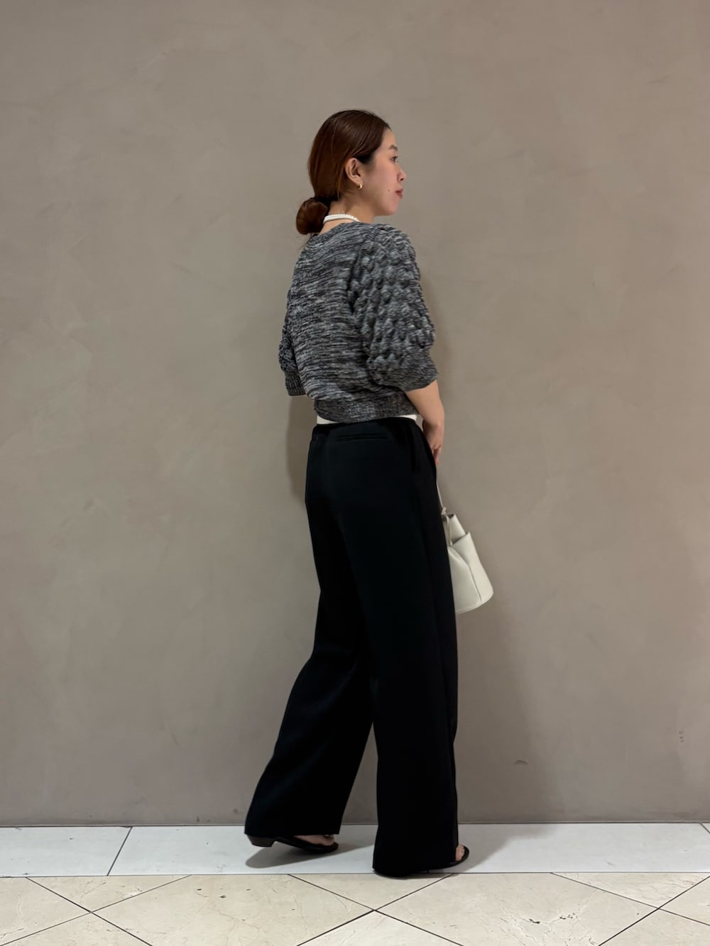 グレー系のニット/セーター、ブラック系のその他パンツ、ホワイト系のハンドバッグを着用したレディースの夏コーディネートの4枚目の写真