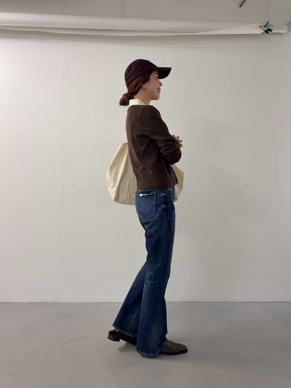 ブラウン系のニット/セーター、ホワイト系のトートバッグ、ブラウン系のスリッポンを着用したレディースの秋コーディネートの4枚目の写真
