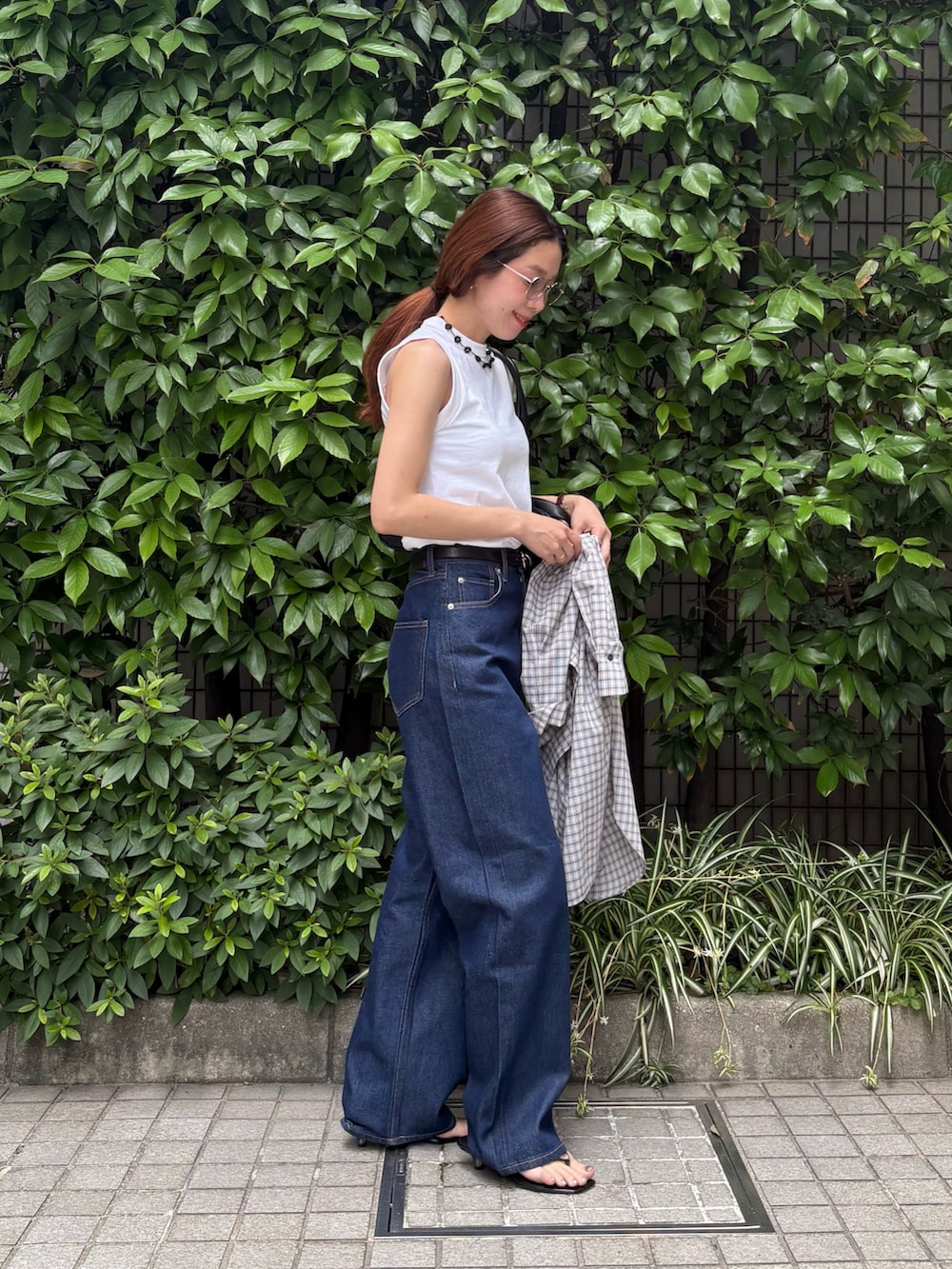 ブルー系のデニムパンツ、ブラック系のショルダーバッグ、ホワイト系のタンクトップを着用したレディースの夏コーディネートの6枚目の写真
