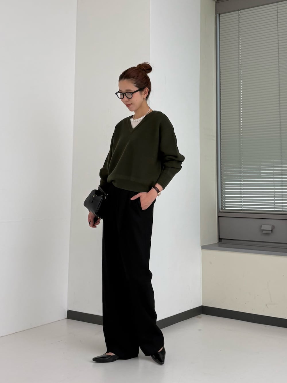 グリーン系のニット/セーター、ホワイト系のTシャツ/カットソー、ブラウン系のハンドバッグを着用したレディースの秋コーディネートの2枚目の写真