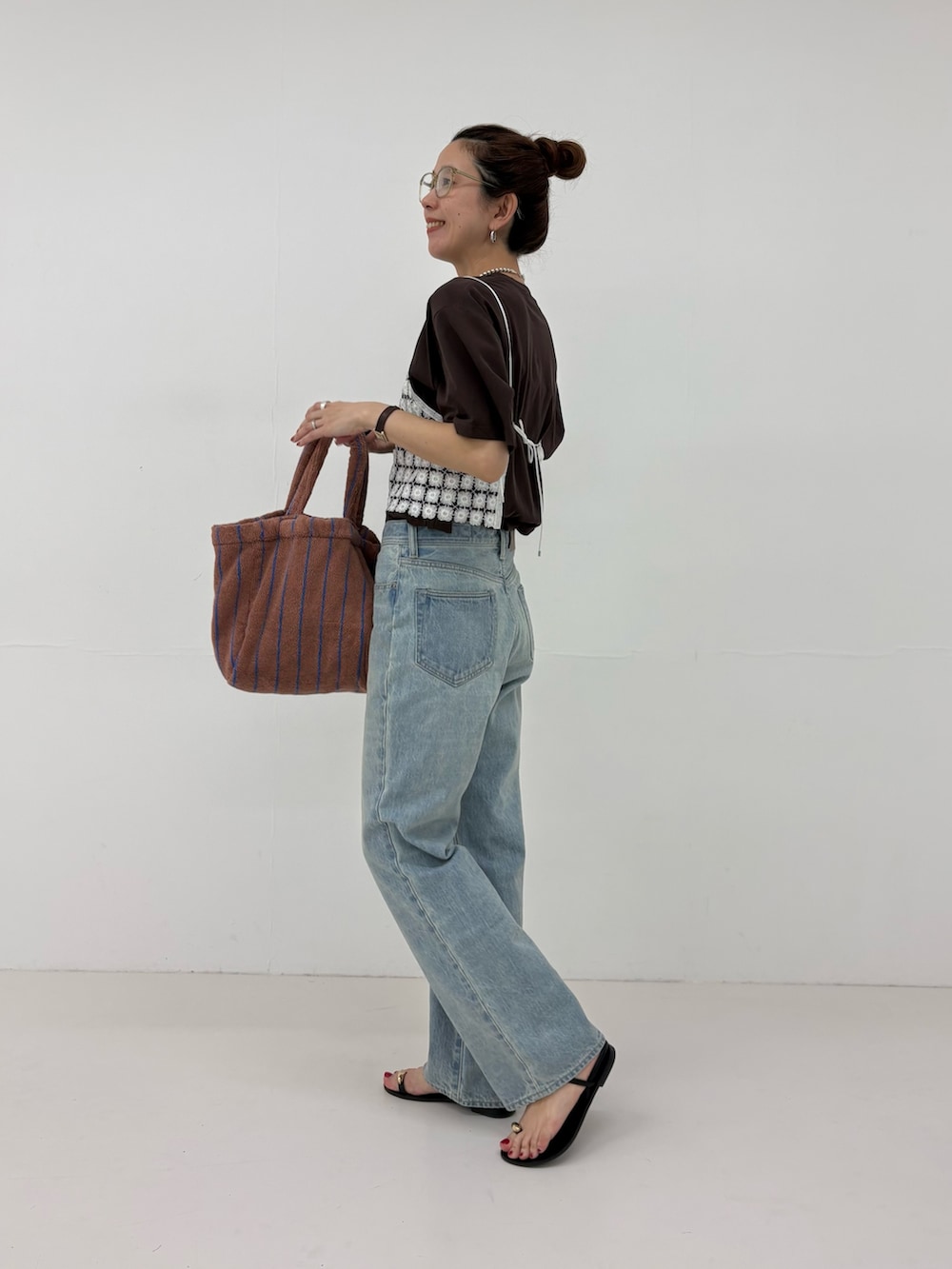 ブルー系のデニムパンツ、ホワイト系のその他トップス、イエロー系のハンドバッグを着用したレディースの春コーディネートの2枚目の写真