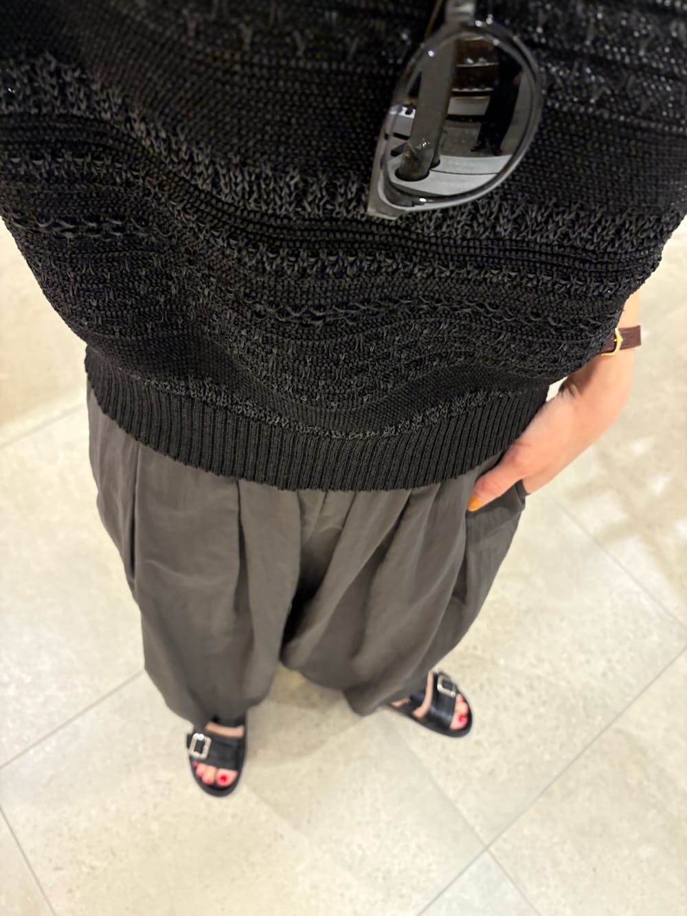 グレー系のその他パンツ、ブラック系のニット/セーター、ホワイト系のハンドバッグを着用したレディースの春コーディネートの7枚目の写真