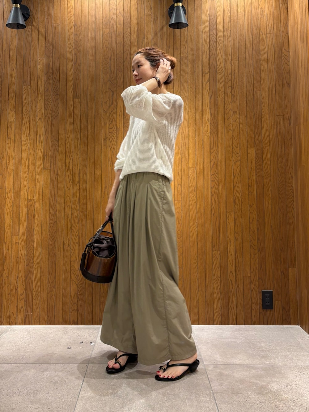ホワイト系のニット/セーター、ベージュ系のその他パンツ、ブラウン系のかごバッグを着用したレディースの春コーディネートの2枚目の写真
