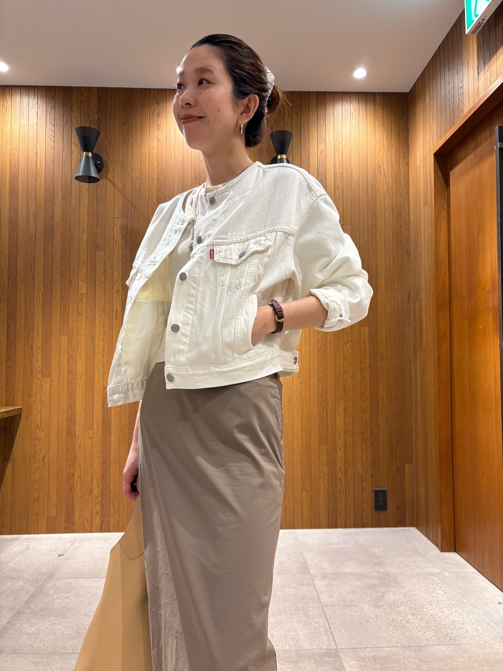 グレー系のスカート、ホワイト系のTシャツ/カットソー、ベージュ系のハンドバッグを着用したレディースの春コーディネートの6枚目の写真