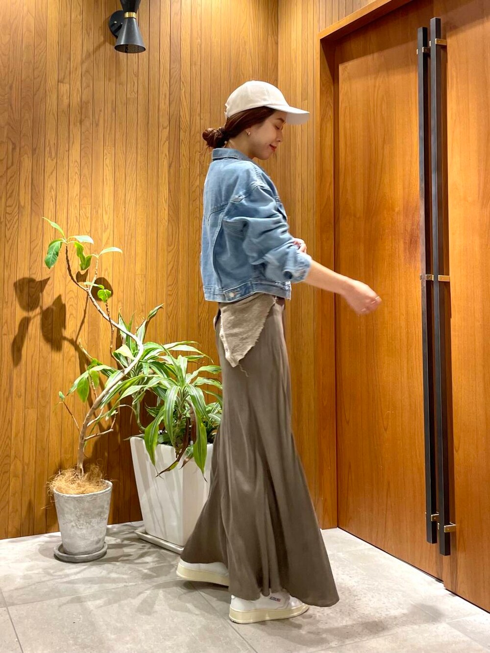 グリーン系のスカート、ブルー系のデニムジャケット、ホワイト系のスニーカーを着用したレディースの秋コーディネートの3枚目の写真