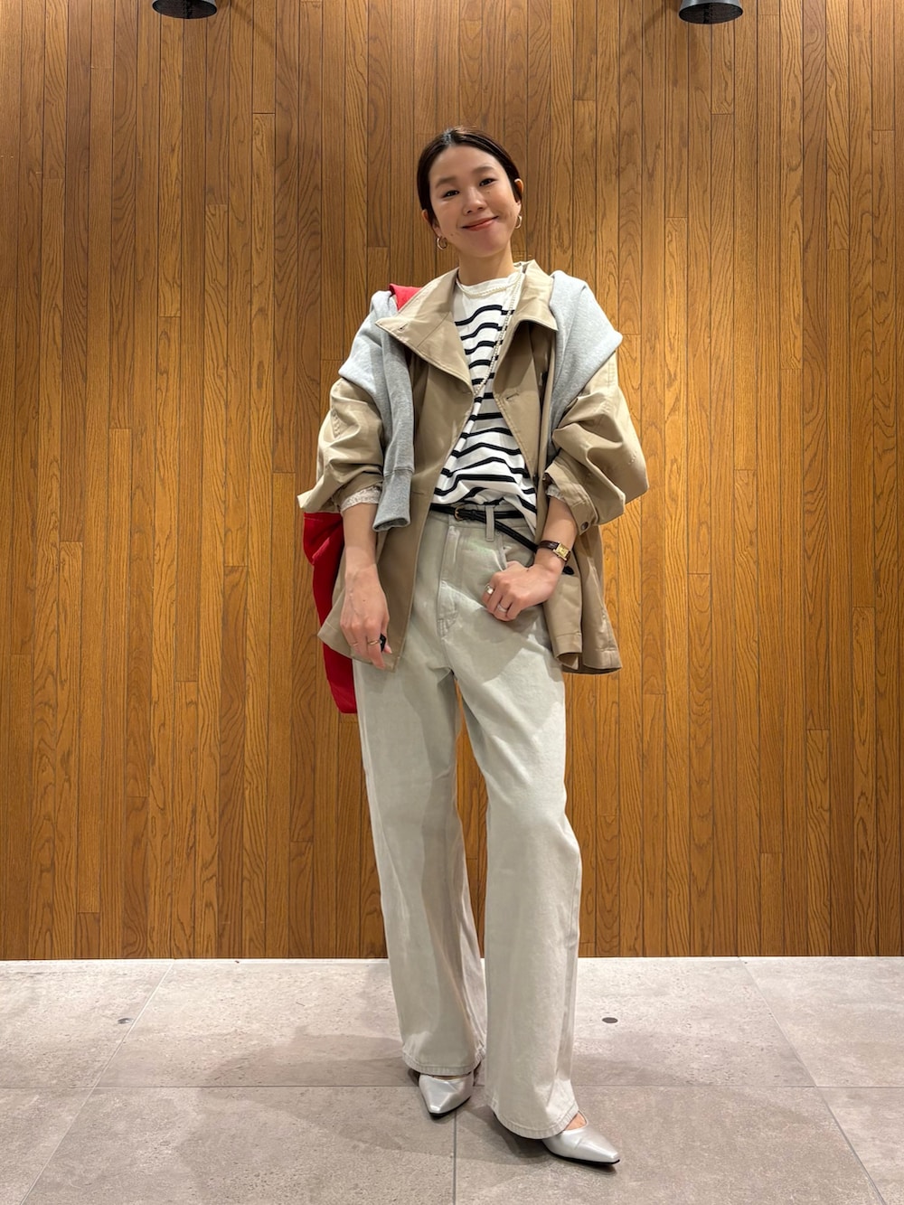 ベージュ系のトレンチコート、グレー系のデニムパンツ、シルバー系のパンプスを着用したレディースの冬コーディネートの5枚目の写真