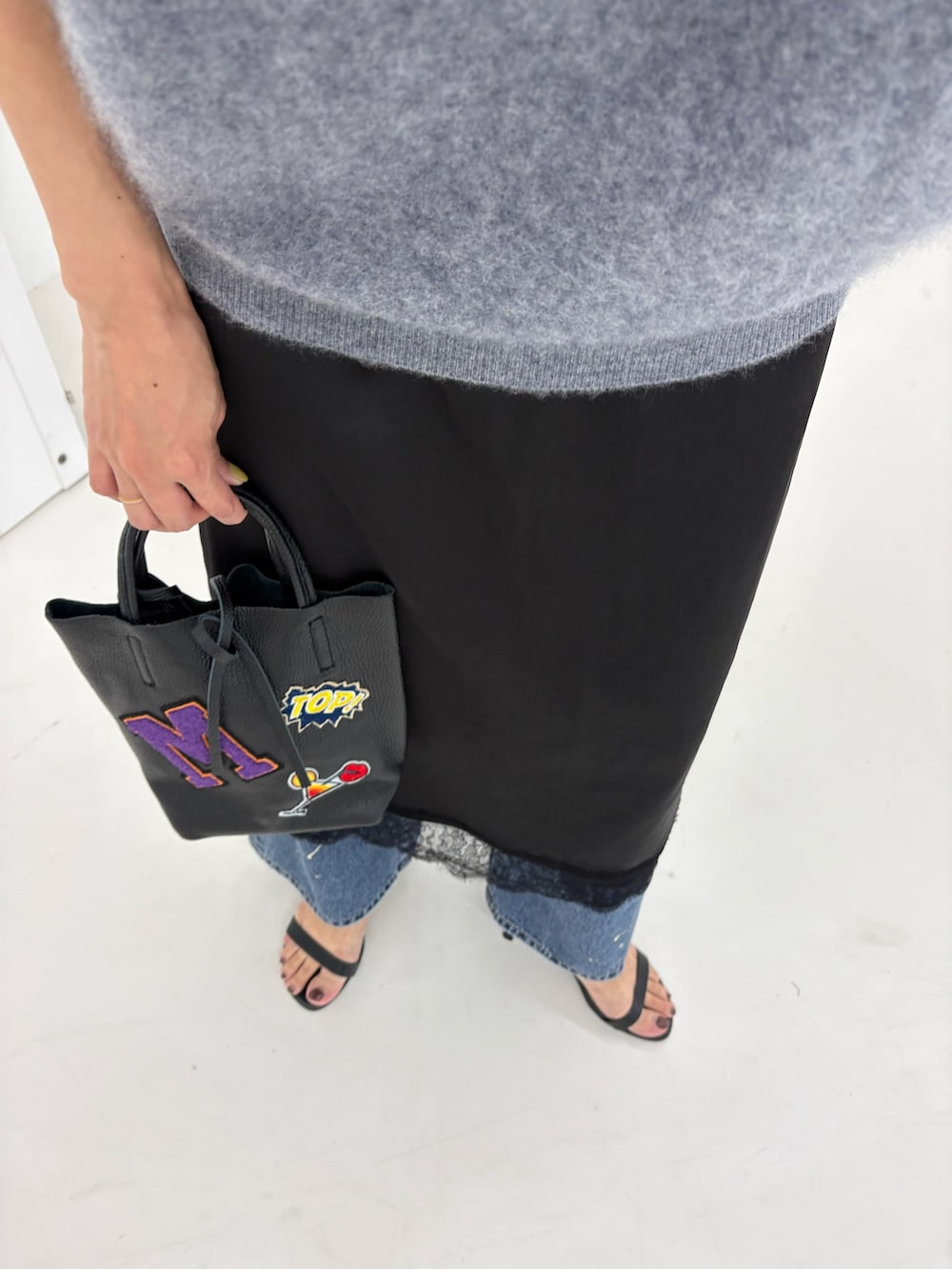 グレー系のニット/セーター、ブラック系のワンピース、ブルー系のデニムパンツを着用したレディースの秋コーディネートの9枚目の写真