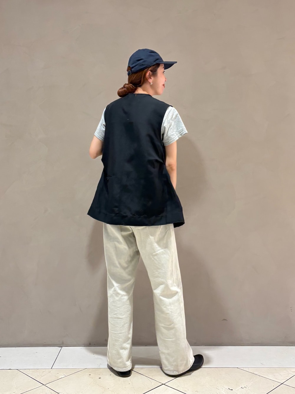グレー系のデニムパンツ、ブラック系のダウンベストを着用したレディースの夏コーディネートの3枚目の写真