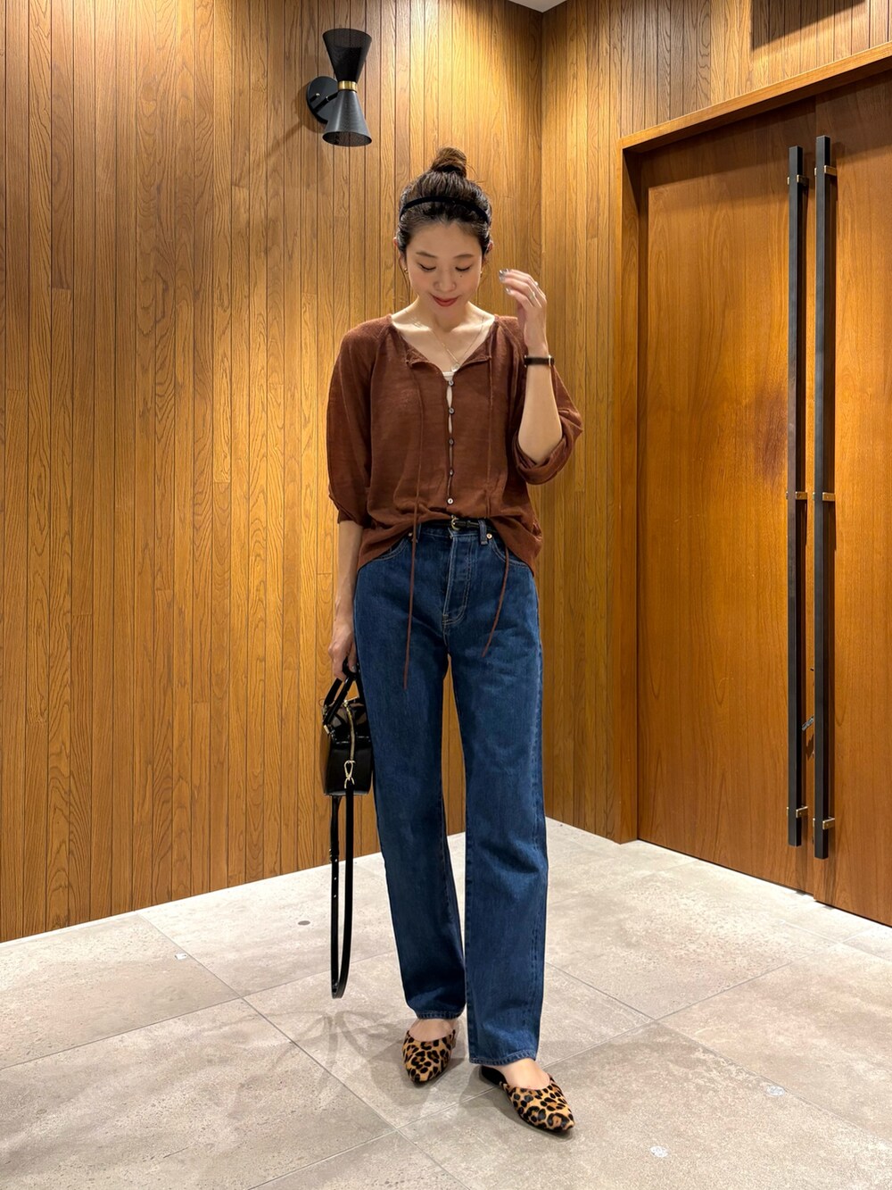 ブルー系のデニムパンツ、ブラック系のショルダーバッグ、ブラウン系のカーディガン/ボレロを着用したレディースの秋コーディネートの2枚目の写真