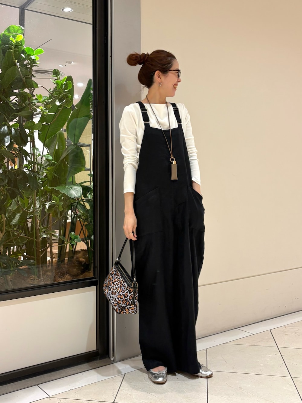 ブラック系のサロペット/オーバーオール、ホワイト系のTシャツ/カットソー、パープル系のハンドバッグを着用したレディースの春コーディネートの2枚目の写真