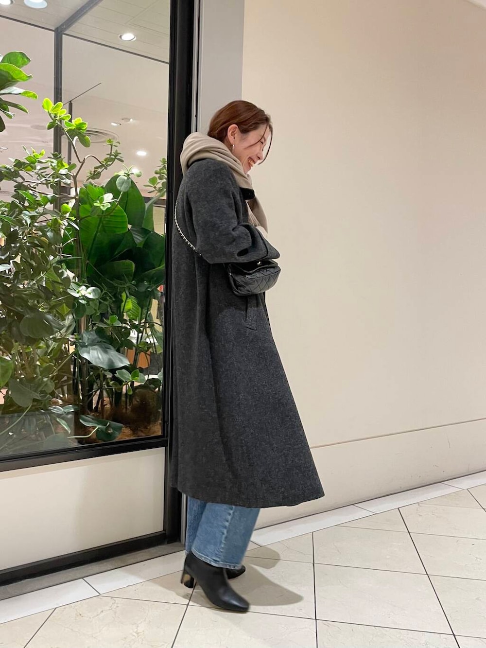 ブルー系のデニムパンツ、ブラック系のショルダーバッグ、レッド系のニット/セーターを着用したレディースの冬コーディネートの4枚目の写真