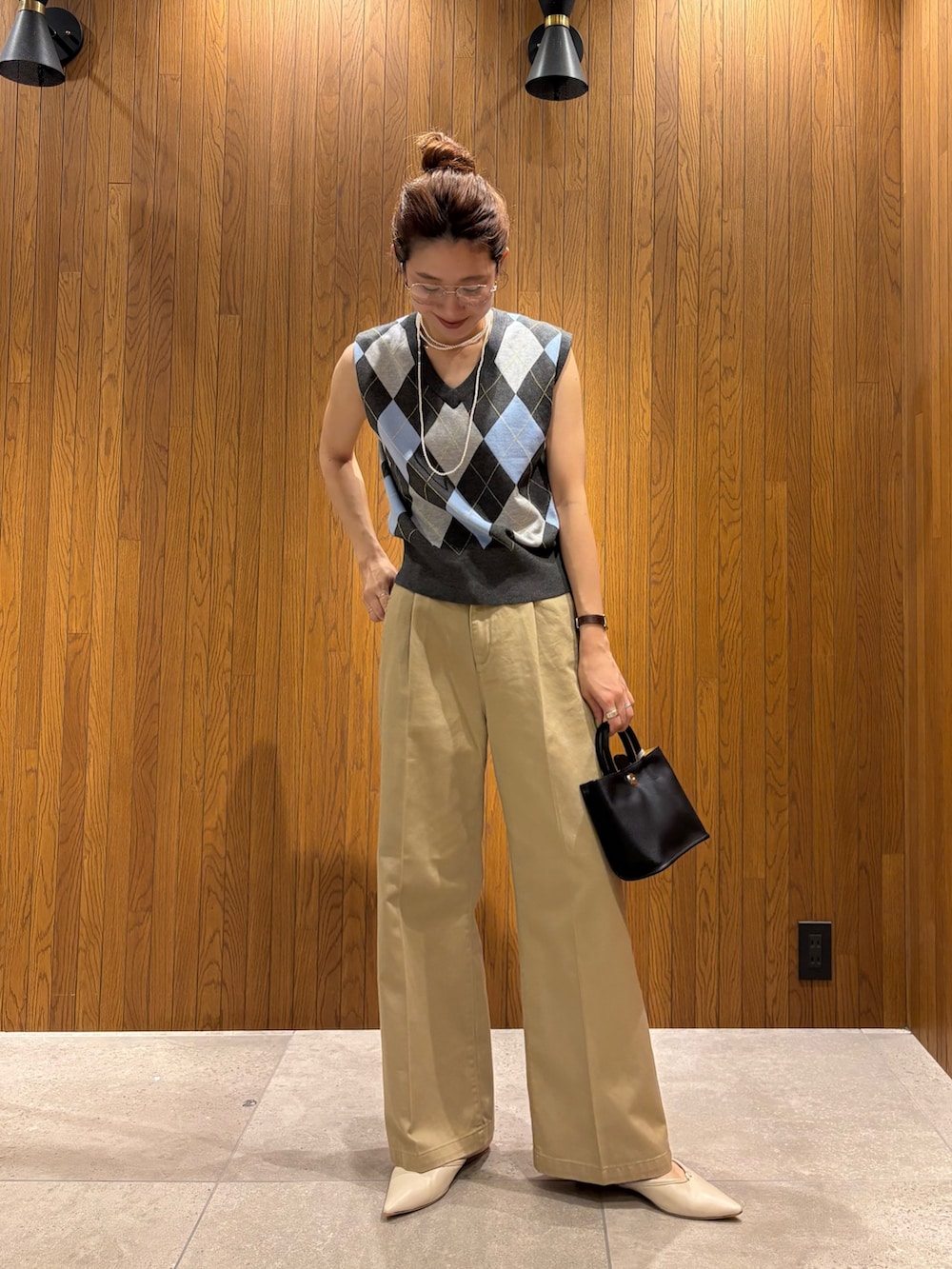 グレー系のベスト、ベージュ系のその他パンツ、ブラック系のハンドバッグを着用したレディースの夏コーディネートの2枚目の写真