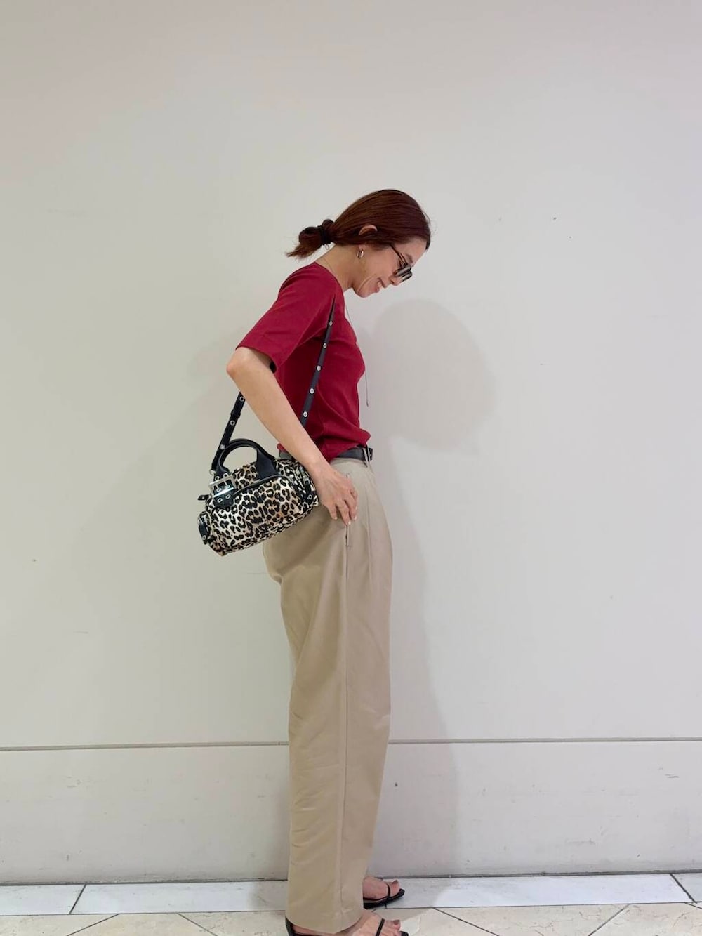 ベージュ系のチノパンツ、ブラック系のサンダル、レッド系のTシャツ/カットソーを着用したレディースの夏コーディネートの2枚目の写真