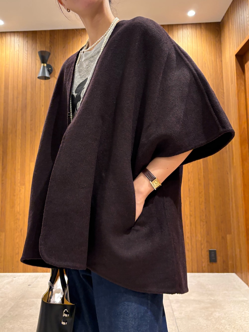 レッド系のポンチョ、ブルー系のデニムパンツ、ブラック系のトートバッグを着用したレディースの秋コーディネートの10枚目の写真