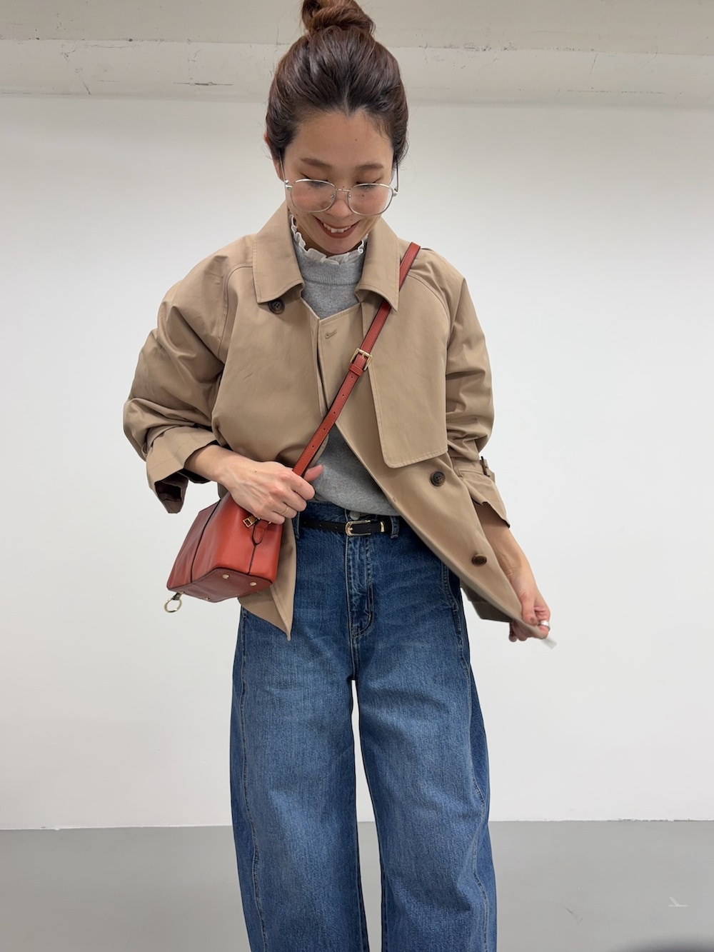 ベージュ系のトレンチコート、ブルー系のデニムパンツ、オレンジ系のショルダーバッグを着用したレディースの冬コーディネートの5枚目の写真