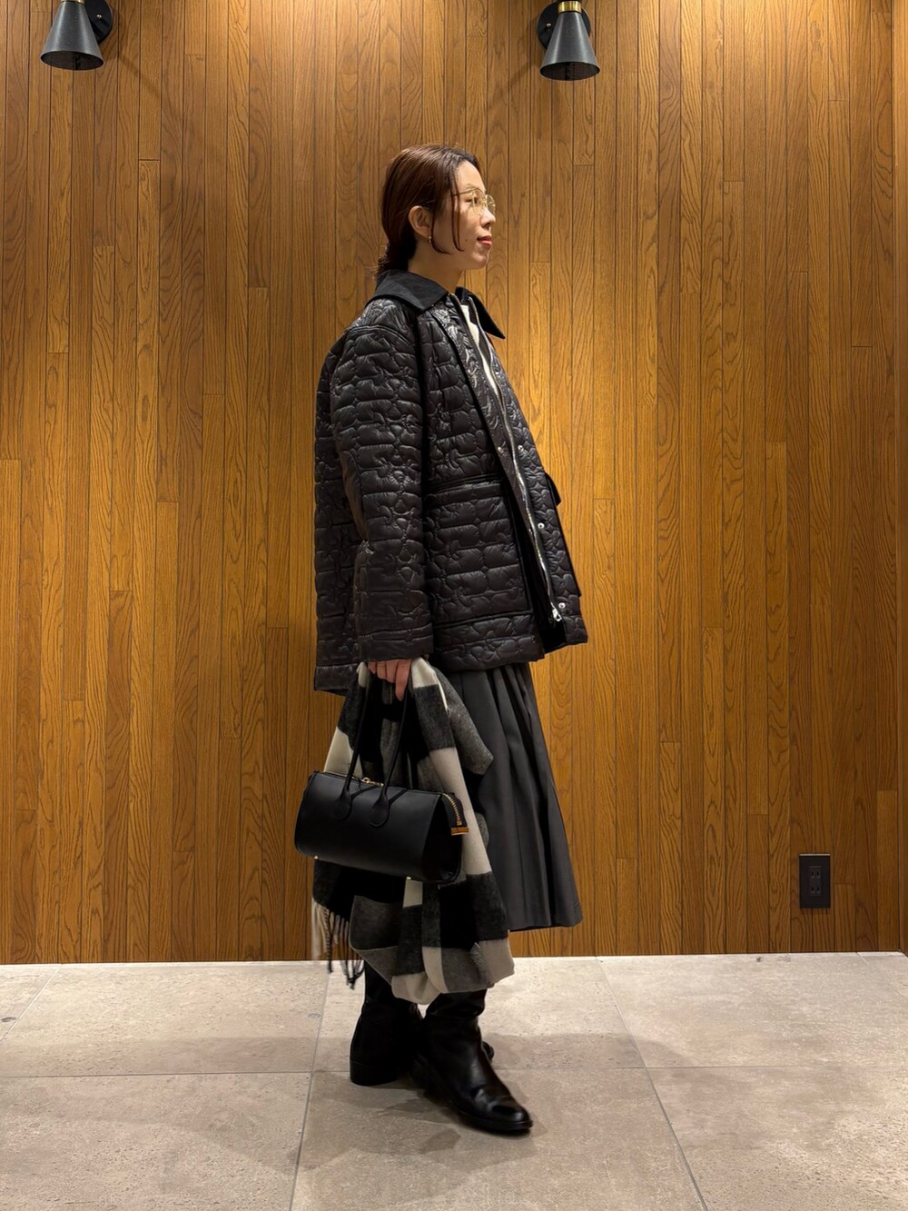 グレー系のダウンジャケット/コート、グリーン系のスカート、ブラック系のショルダーバッグを着用したレディースの冬コーディネートの2枚目の写真