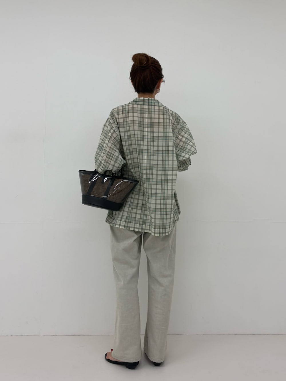 ブラック系のかごバッグ、グレー系のデニムパンツ、ブラック系のサンダルを着用したレディースの春コーディネートの4枚目の写真