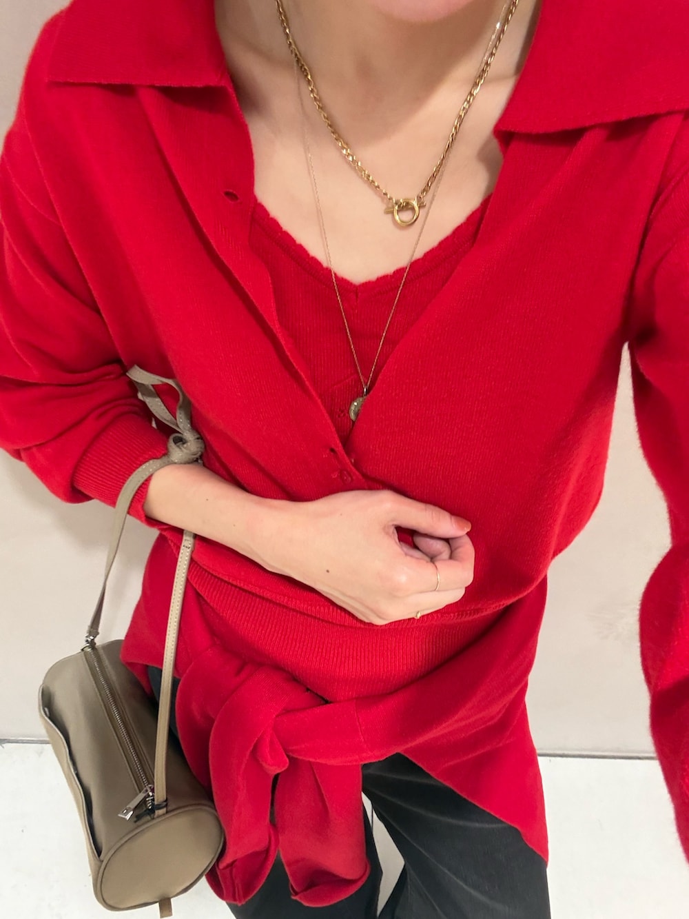 レッド系のニット/セーター、ブラック系のデニムパンツ、グレー系のスニーカーを着用したレディースの秋コーディネートの7枚目の写真
