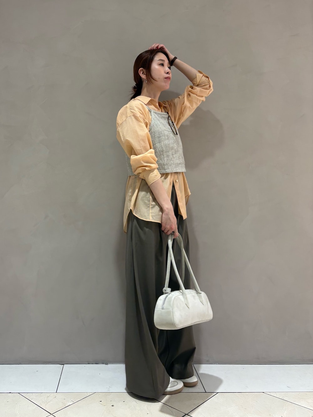 オレンジ系のシャツ/ブラウス、ベージュ系のその他トップス、ホワイト系のスニーカーを着用したレディースの春コーディネートの2枚目の写真