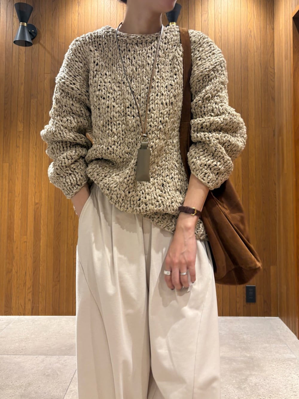 グレー系のニット/セーター、ホワイト系のその他パンツ、ブラウン系のトートバッグを着用したレディースの秋コーディネートの6枚目の写真