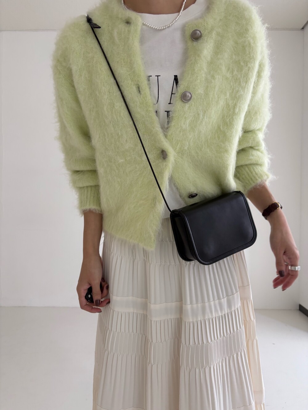 ホワイト系のスカート、グリーン系のカーディガン/ボレロ、ブラック系のブーツを着用したレディースの秋コーディネートの6枚目の写真