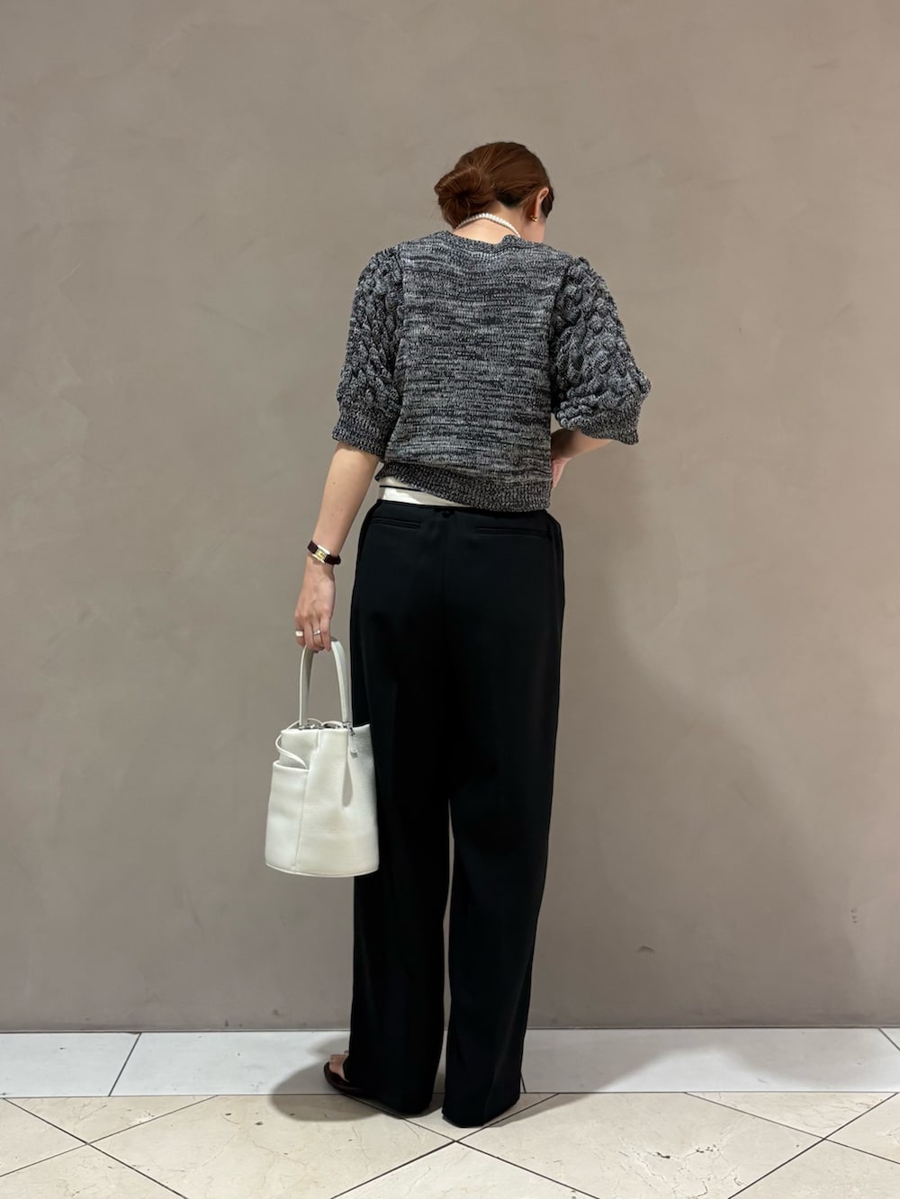 グレー系のニット/セーター、ブラック系のその他パンツ、ホワイト系のハンドバッグを着用したレディースの夏コーディネートの3枚目の写真