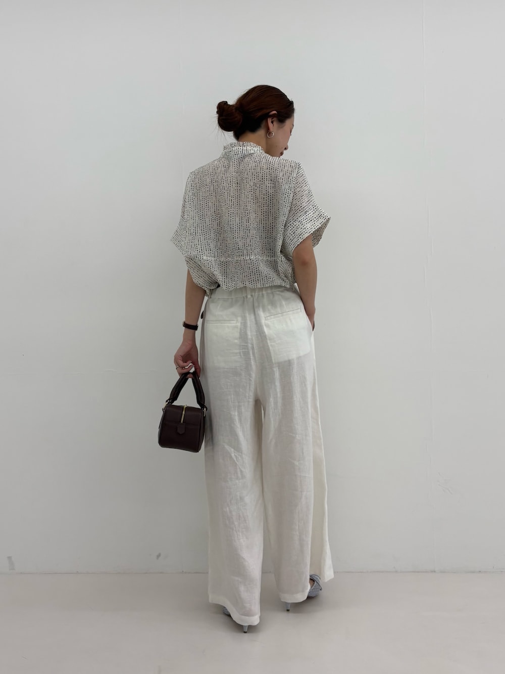 ホワイト系のシャツ/ブラウス、ホワイト系のその他パンツ、ブラウン系のハンドバッグを着用したレディースの春コーディネートの3枚目の写真