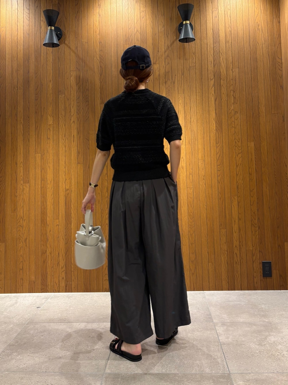 グレー系のその他パンツ、ブラック系のニット/セーター、ホワイト系のハンドバッグを着用したレディースの春コーディネートの3枚目の写真