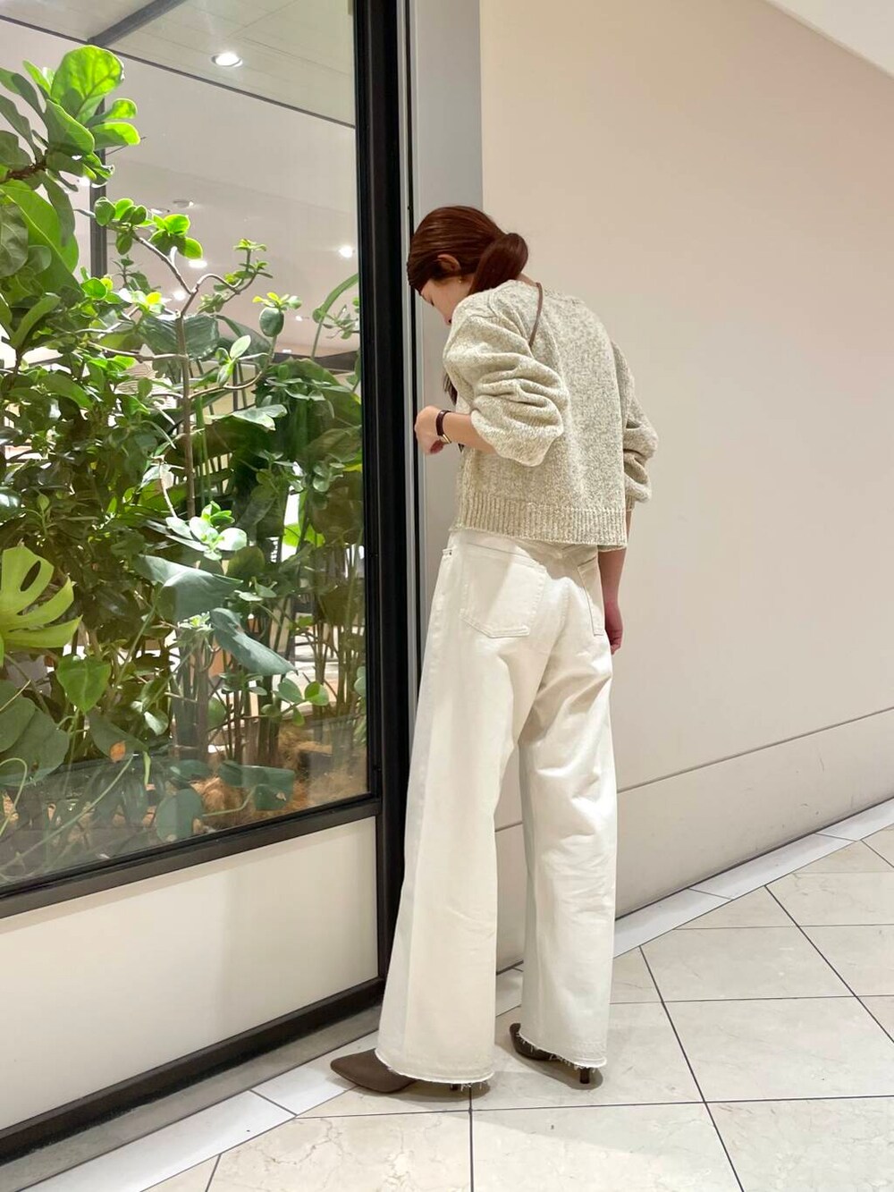ホワイト系のデニムパンツ、ブラウン系のブーツ、ホワイト系のニット/セーターを着用したレディースの秋コーディネートの2枚目の写真