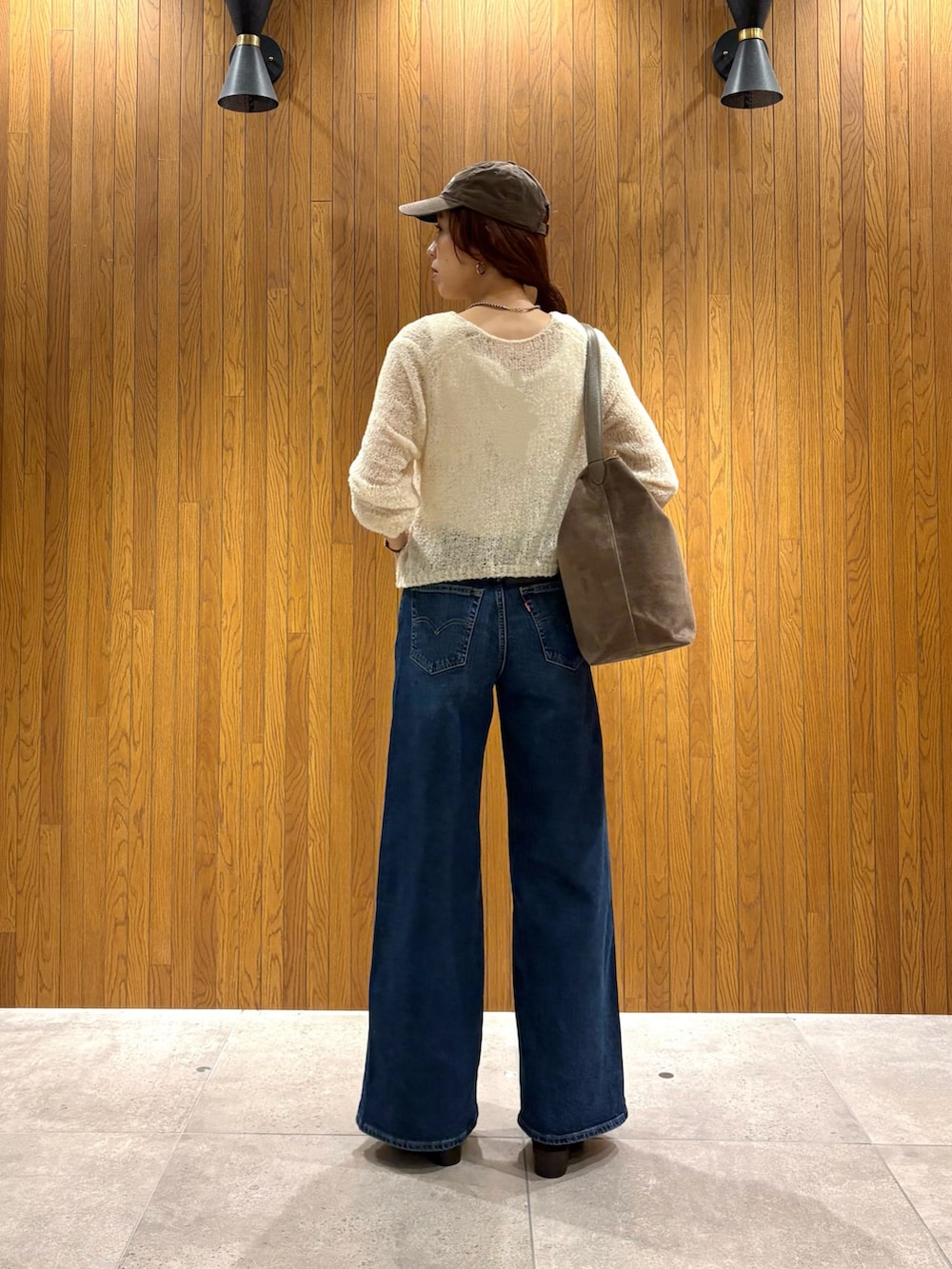 ブルー系のデニムパンツ、ブラウン系のトートバッグ、ベージュ系のブーツを着用したレディースの秋コーディネートの3枚目の写真