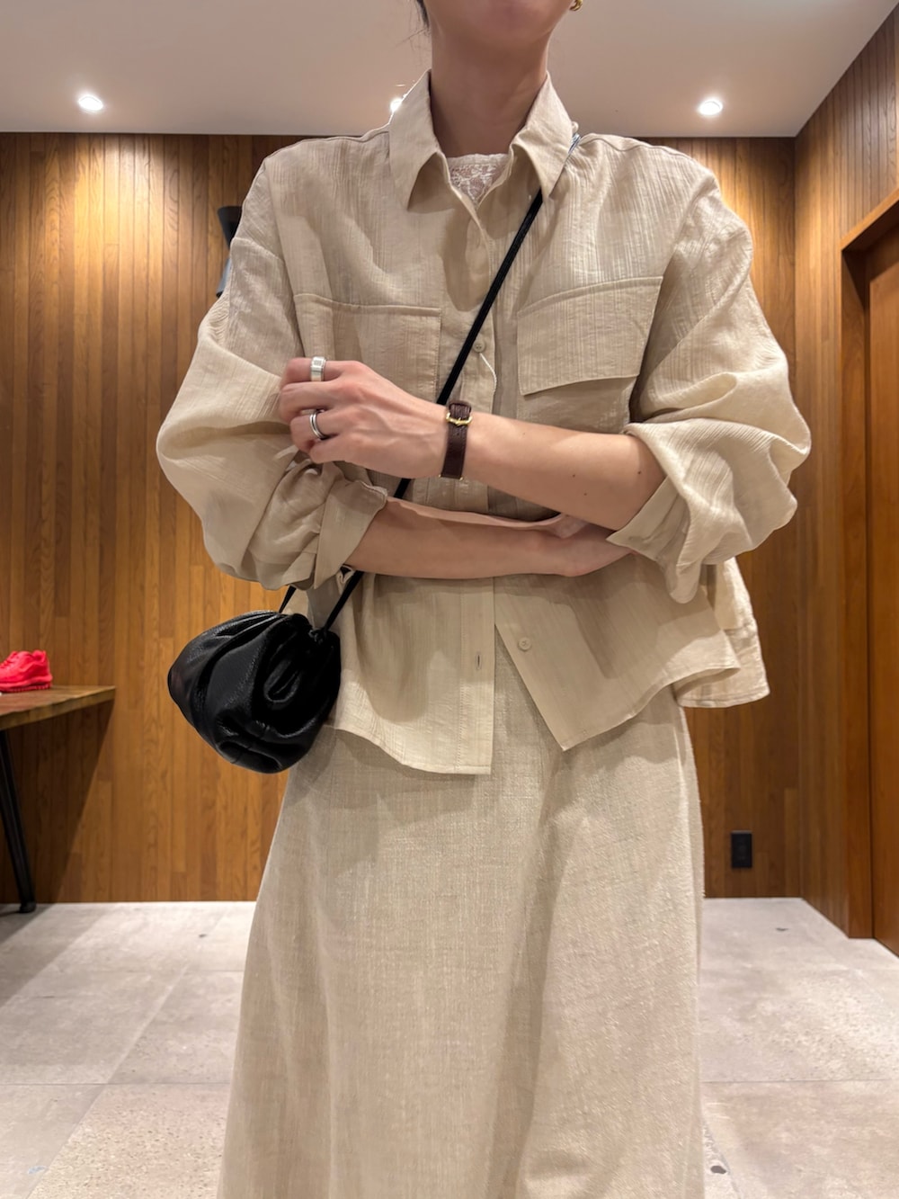 ベージュ系のスカート、ホワイト系のシャツ/ブラウス、ブラック系のショルダーバッグを着用したレディースの春コーディネートの5枚目の写真
