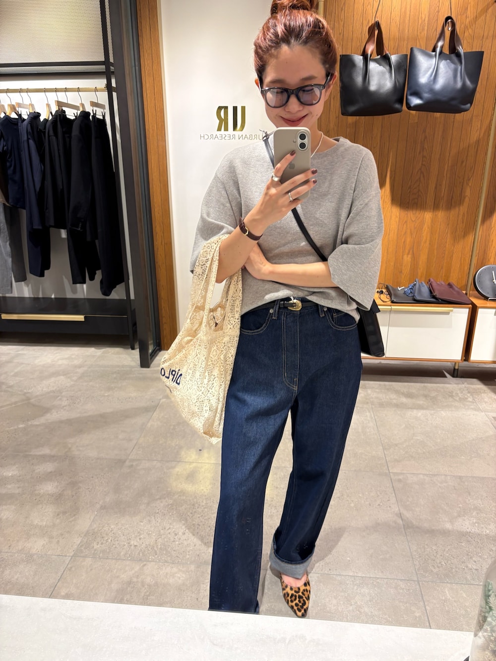 ホワイト系のハンドバッグ、ブルー系のデニムパンツ、ブラック系のショルダーバッグを着用したレディースの秋コーディネートの6枚目の写真
