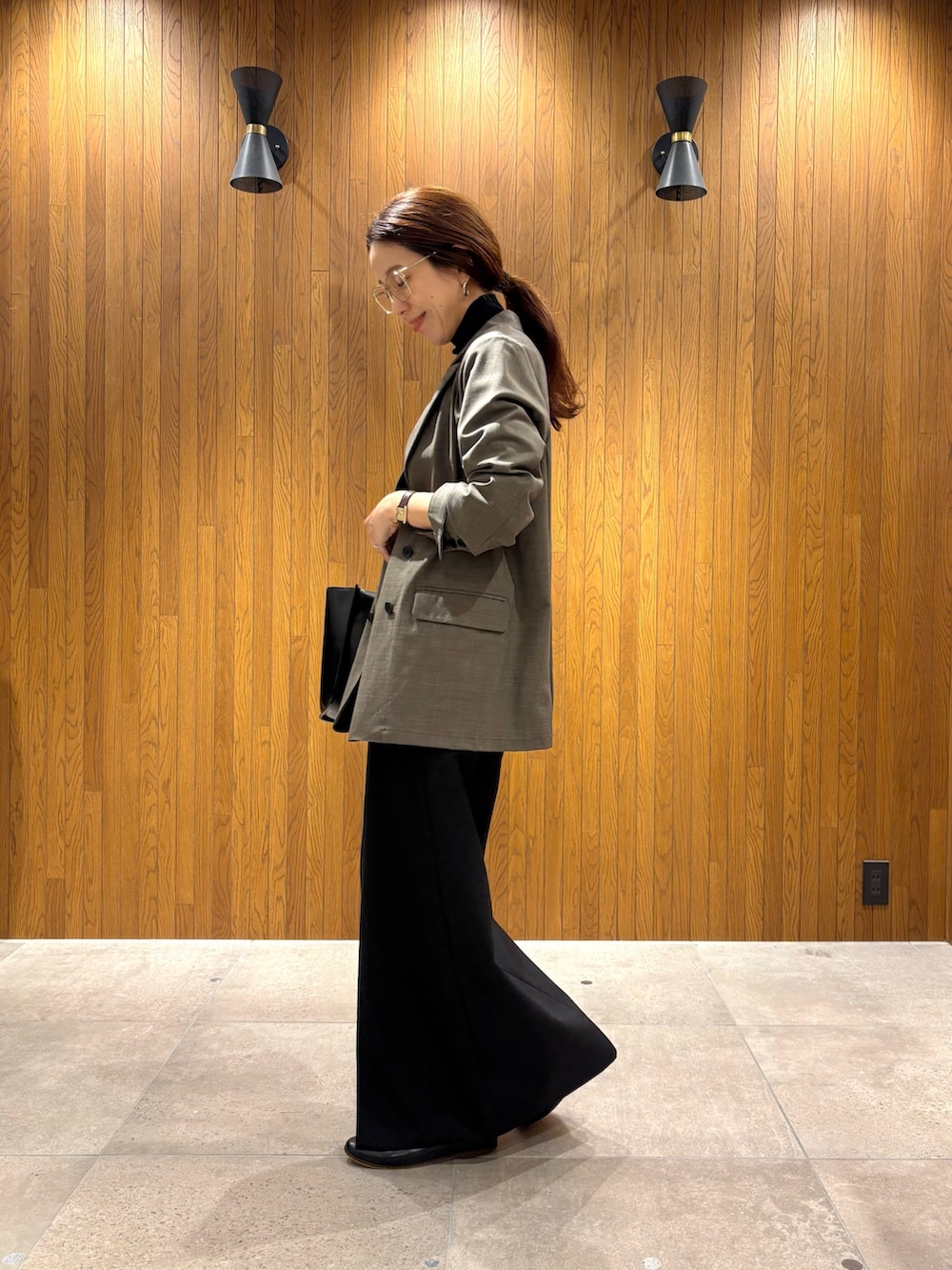 ブラック系のスカート、ブラック系のニット/セーター、ブラック系のハンドバッグを着用したレディースの秋コーディネートの4枚目の写真