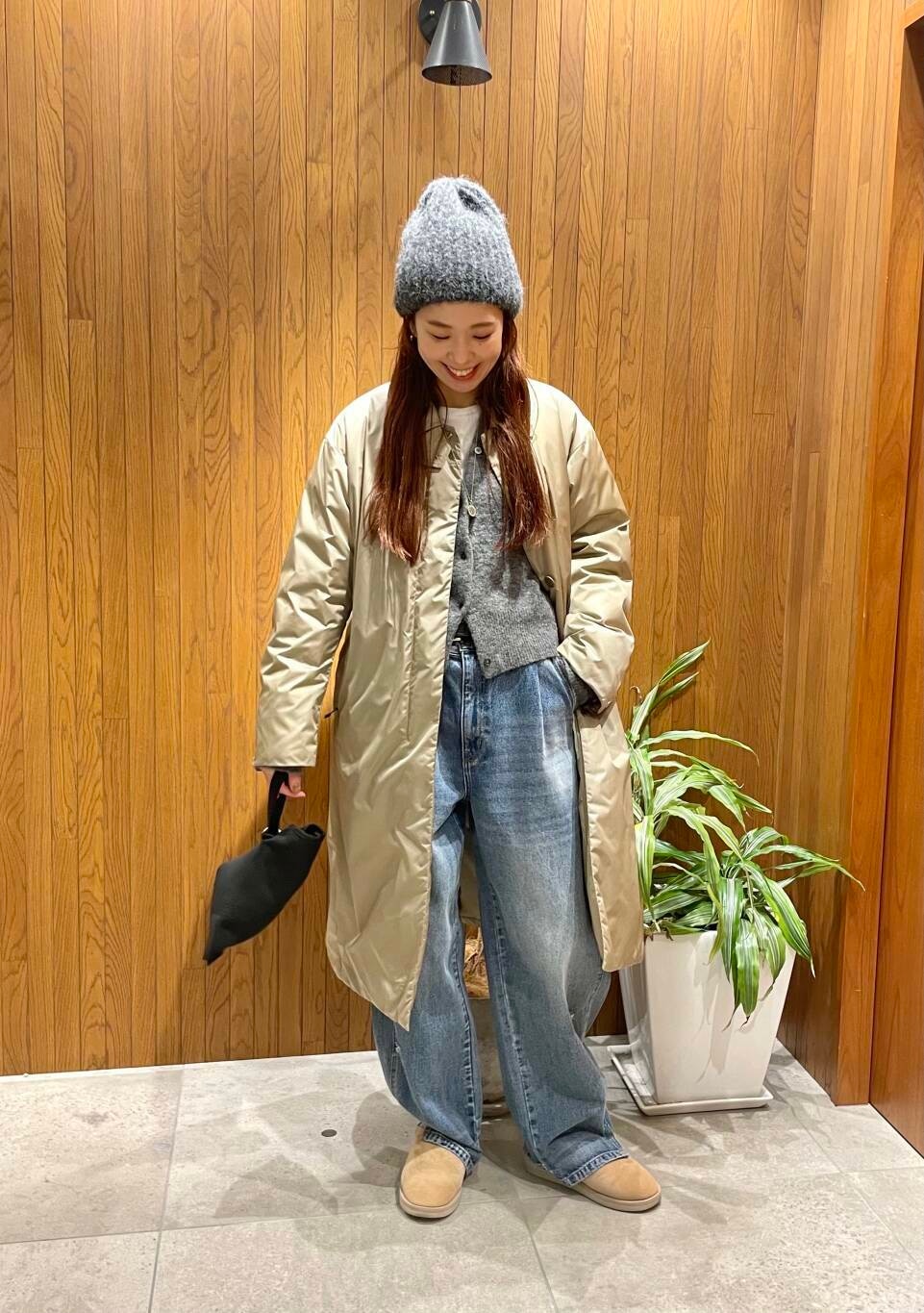 ブルー系のデニムパンツ、グレー系のカーディガン/ボレロ、ベージュ系のダウンジャケット/コートを着用したレディースの秋コーディネートの2枚目の写真