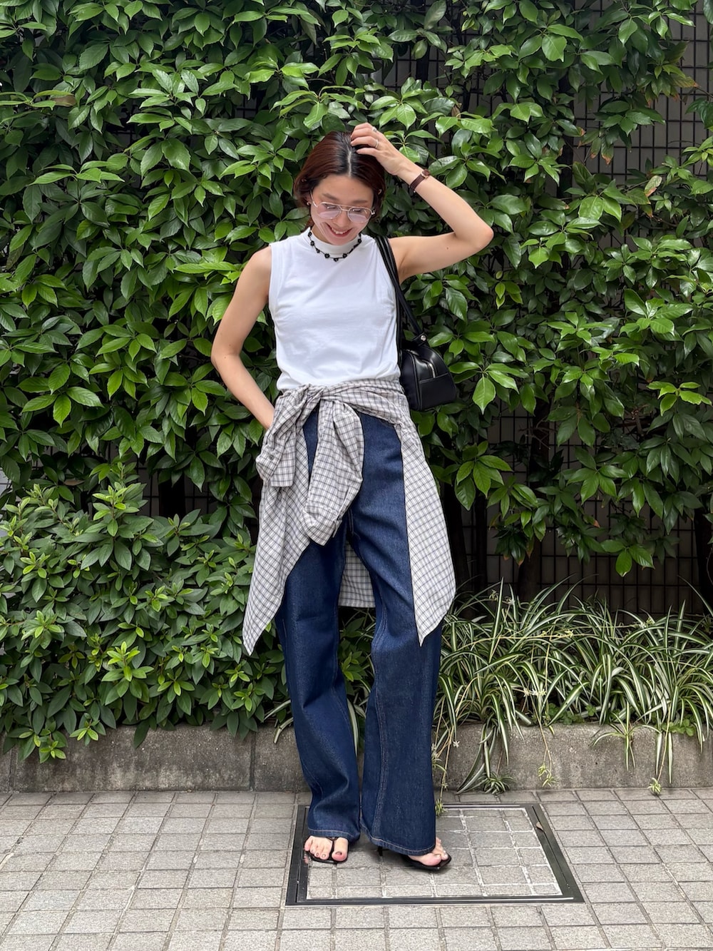 ブルー系のデニムパンツ、ブラック系のショルダーバッグ、ホワイト系のタンクトップを着用したレディースの夏コーディネートの5枚目の写真
