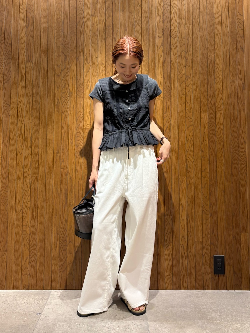 ホワイト系のデニムパンツ、ベージュ系のサンダル、ブラック系のかごバッグを着用したレディースの夏コーディネートの5枚目の写真