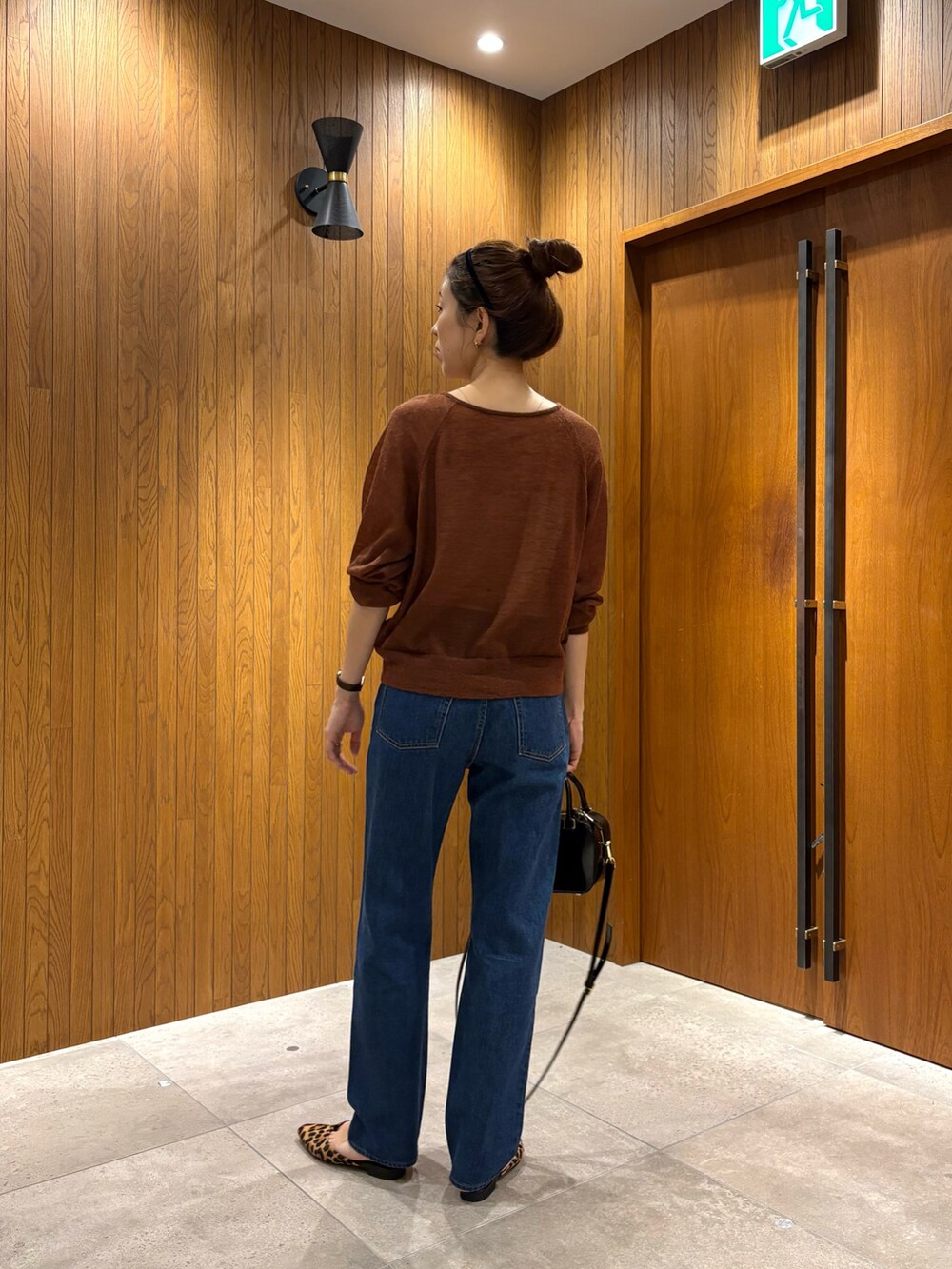 ブルー系のデニムパンツ、ブラック系のショルダーバッグ、ブラウン系のカーディガン/ボレロを着用したレディースの秋コーディネートの5枚目の写真