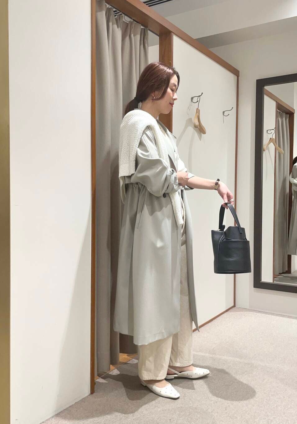 イエロー系のTシャツ/カットソー、グリーン系のトレンチコート、ホワイト系のニット/セーターを着用したレディースの春コーディネートの2枚目の写真